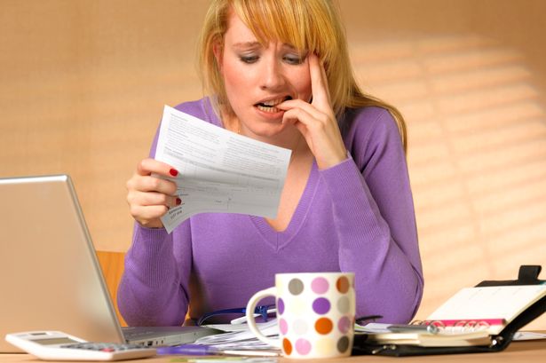 Worried woman reviewing medical bills and health insurance paperwork at a kitchen table