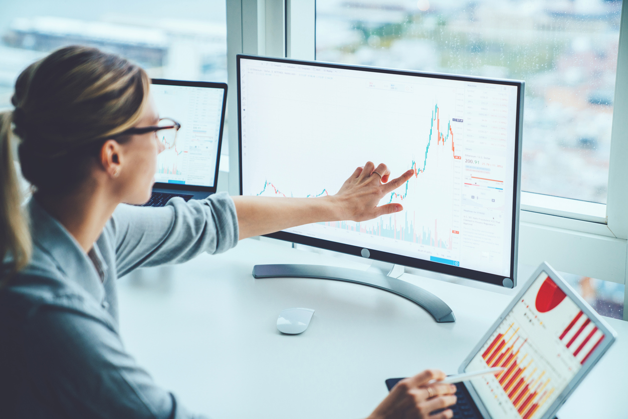 Finance specialist working at multiple computer monitors