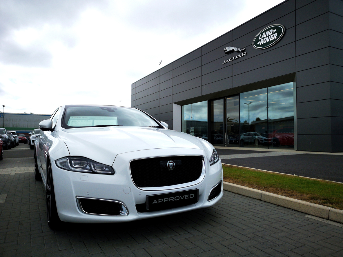 White Jaguar XJ outside Jaguar Land Rover showroom