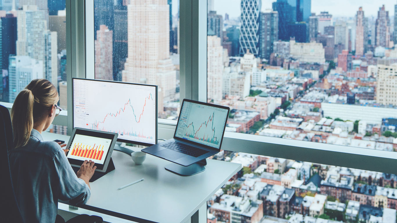 Businesswoman examining stock market in front of skyscraper window