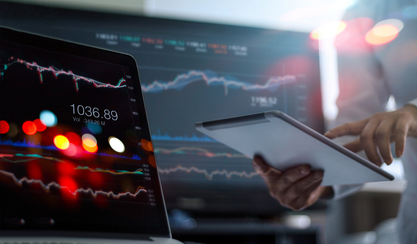 Investor using laptop and tablet to analyse stock market data