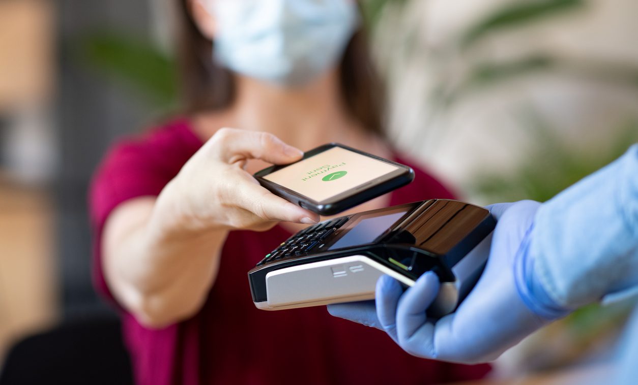 Masked woman making a contactless payment