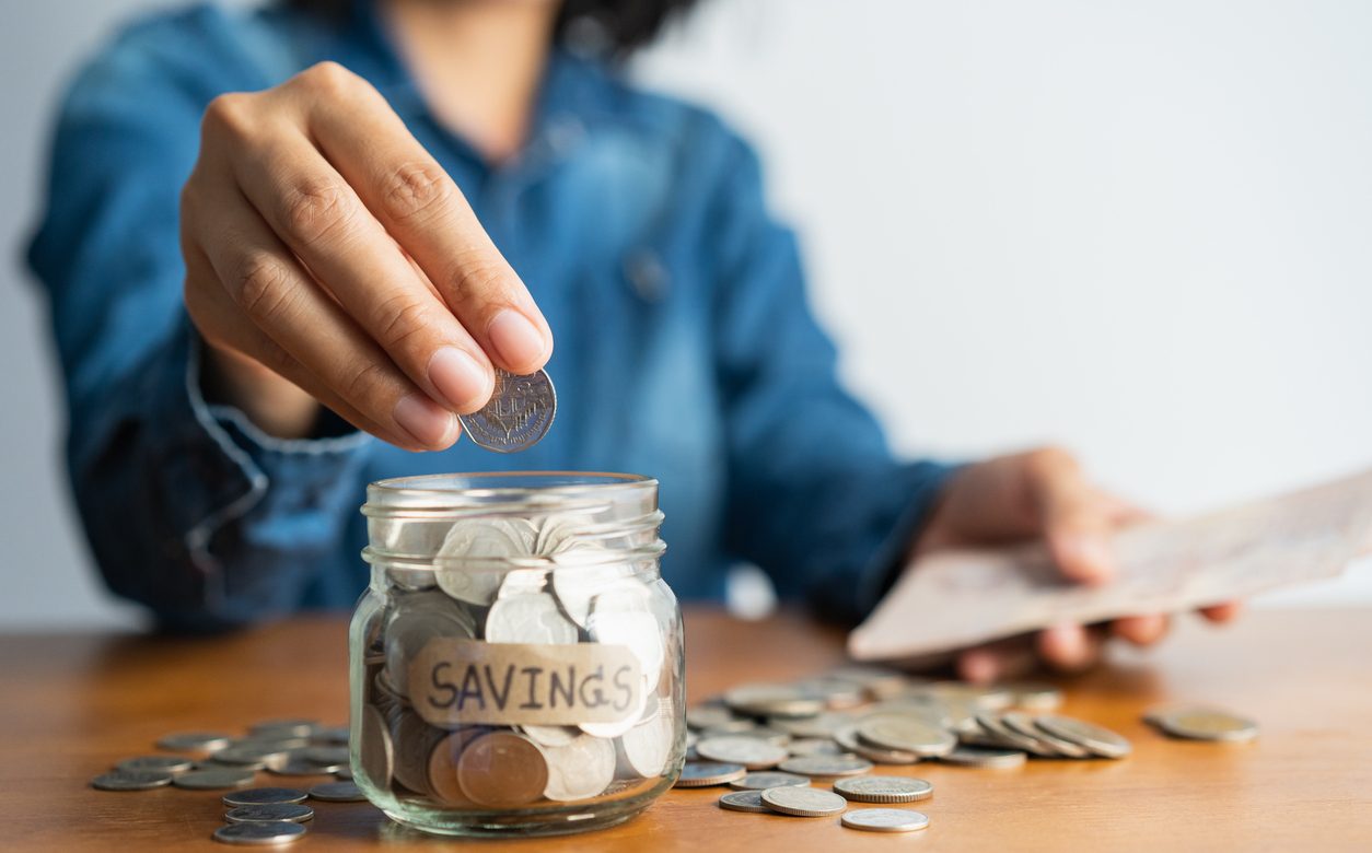 Woman putting coins in a savings jar