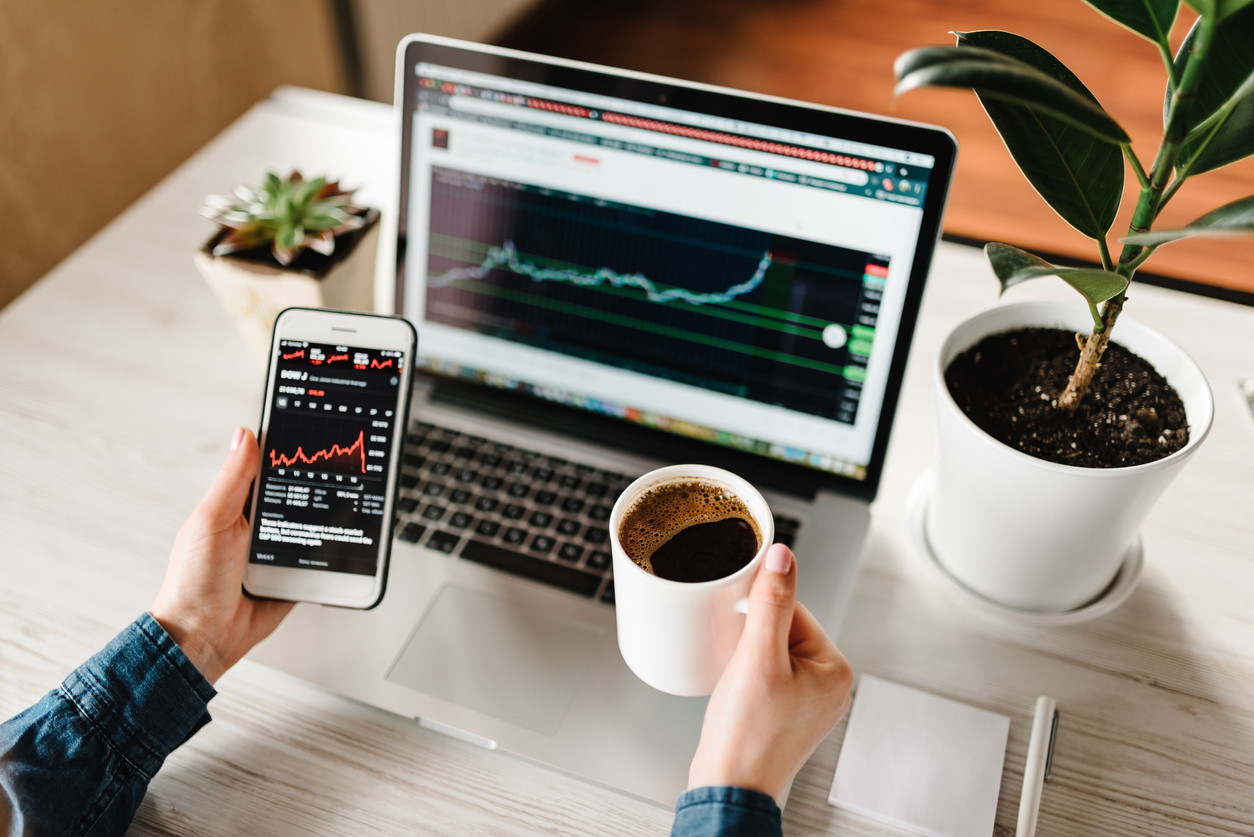 Young woman drinking coffee and trading Forex