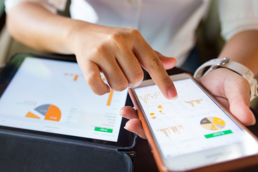 Businesswoman checking market data on a laptop and smartphone