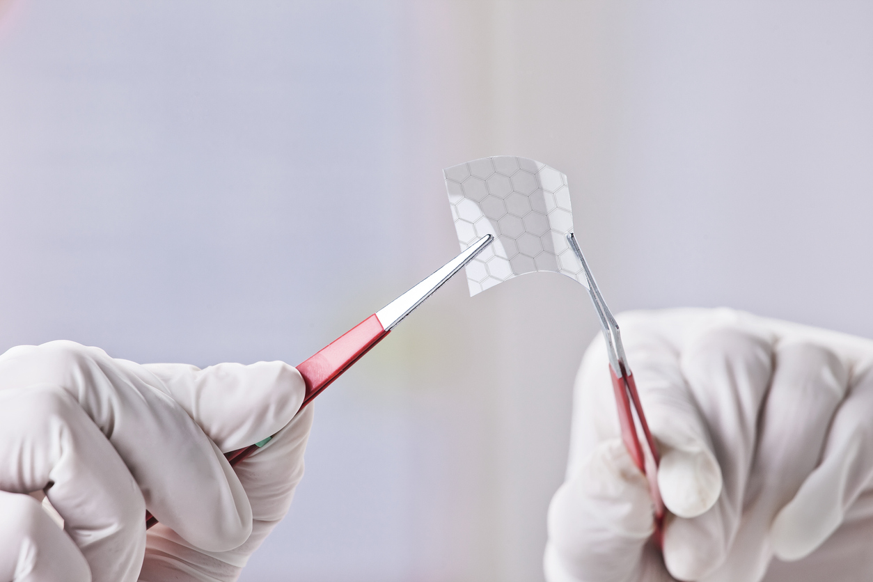 Hands of scientific showing a graphene piece with hexagonal molecule.