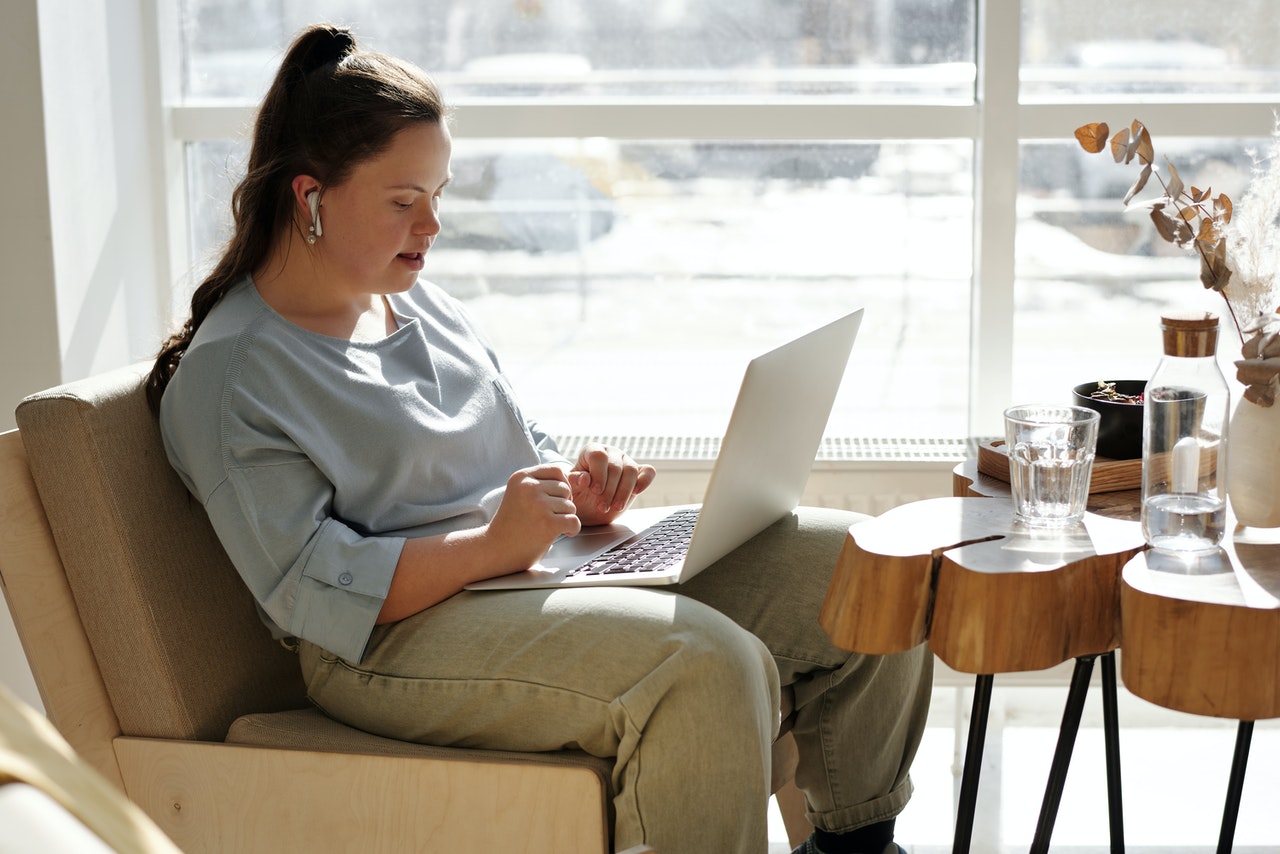Young woman sat on couch, using laptop