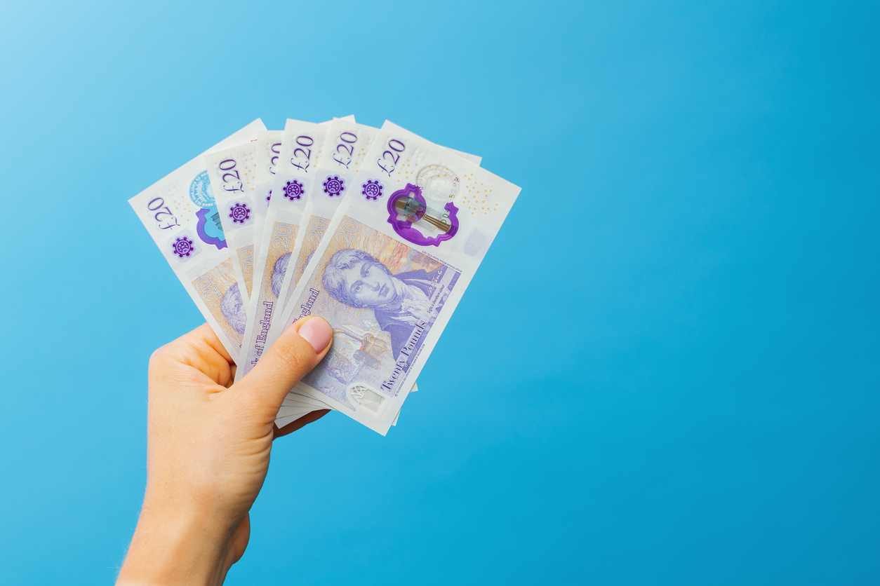 image woman's hands which holds british pounds in her hands isolated over blue studio background.