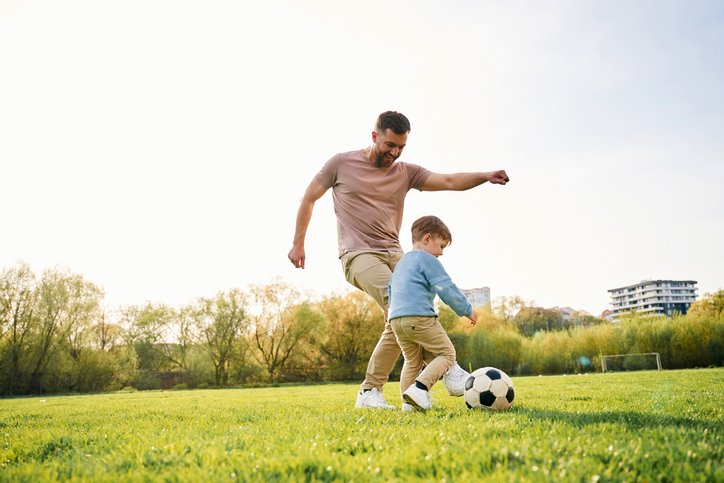 playing soccer. happy father with son are having fun on the field at summertime
