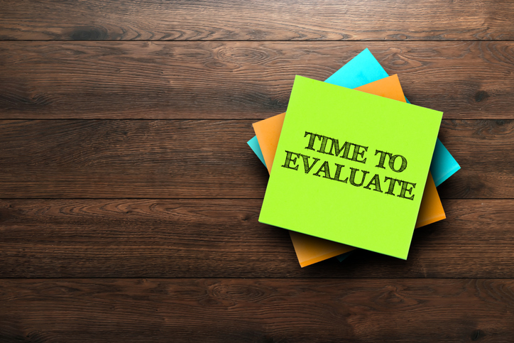 time to evaluate, the phrase is written on multi colored stickers, on a brown wooden background. business concept, strategy, plan, planning.