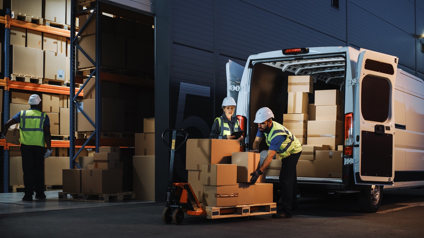 outside of logistics retail warehouse with inventory manager using tablet computer, talking to worker loading delivery truck with cardboard boxes, online orders, food and medicine supply, e commerce