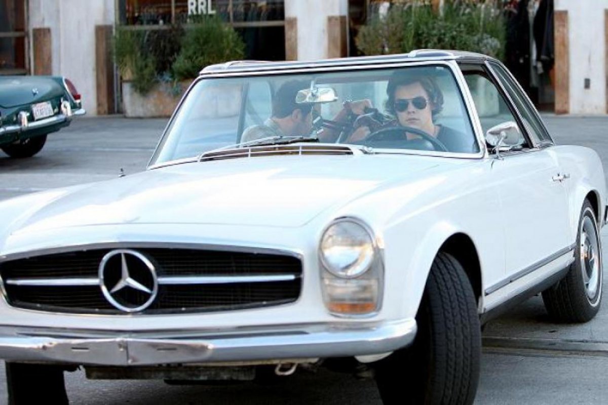 Harry Styles driving his classic Mercedes, highlighting his love for vintage cars and stylish lifestyle.
