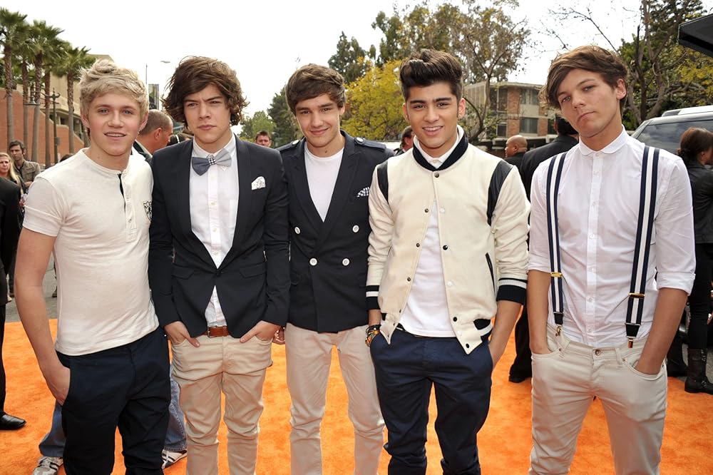 Young One Direction members, including Harry Styles, posing together on the red carpet early in their career.