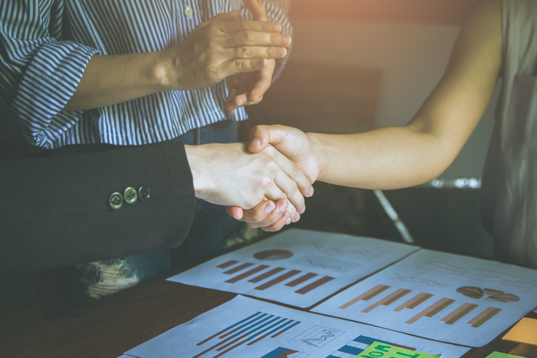 group asian business people put their hands together, handshaking unity mutually beneficial business relationship. finance economic graph on the table. teamwork concept