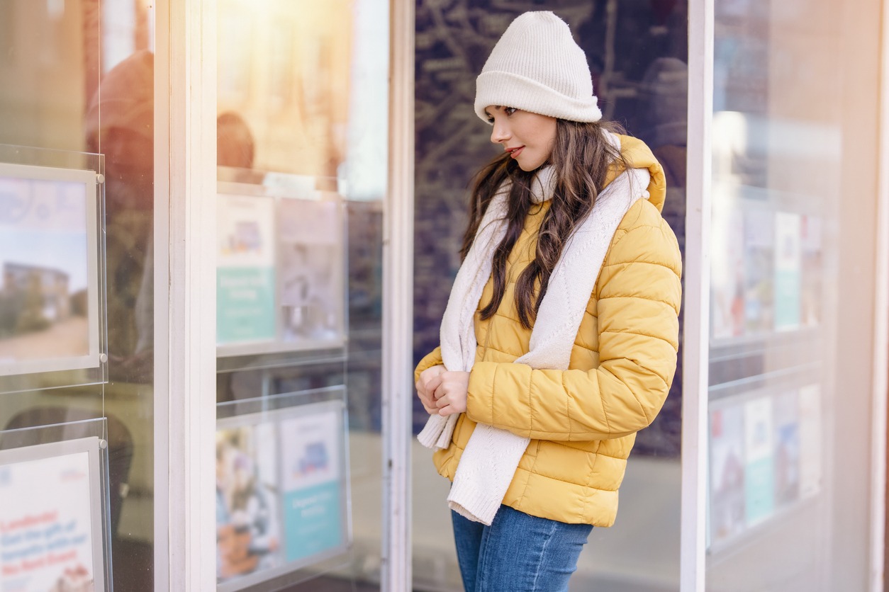 young first time buyer in front of estate agency looking at advertised properties, trying to find affordable house to buy or rent