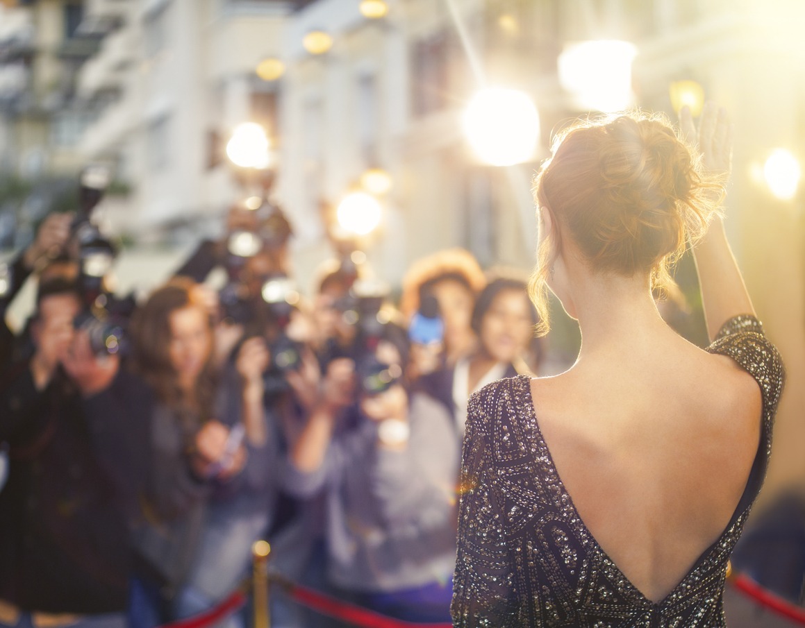celebrity waving at paparazzi photographers at event