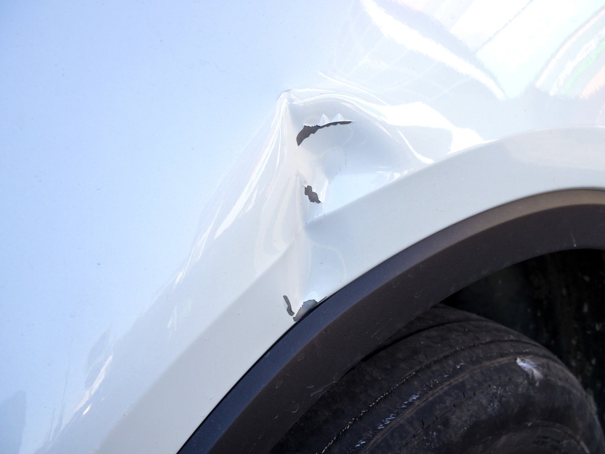 dent on the fender of a white car