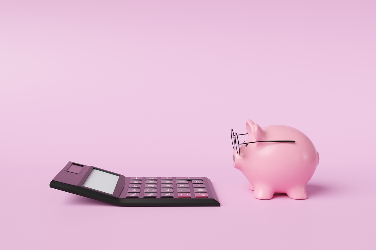 pink piggy bank wearing spectacles in front of a black calculator on pink background. illustration of the concept of commercial accounting, income calculation and retirement planning