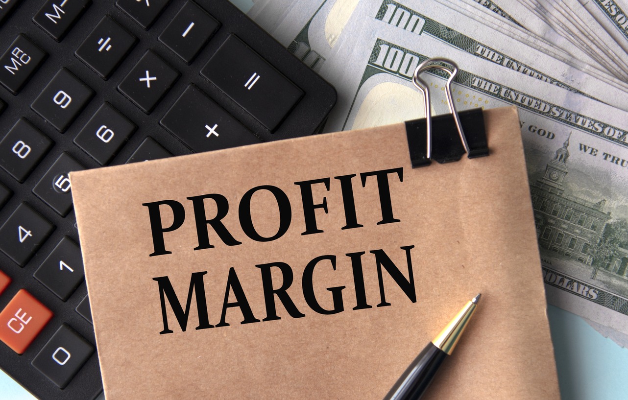 profit margin words on brown paper on the background of calculator and banknotes