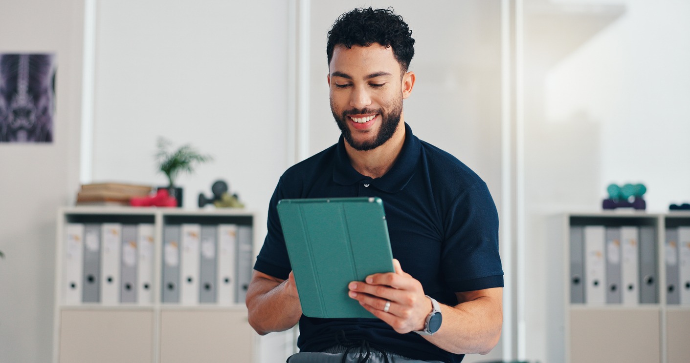 man, physiotherapist and tablet in office with smile, registration and healthcare service. chiropractor, happy and tech in private practice for reflexology, patient schedule and physiotherapy startup