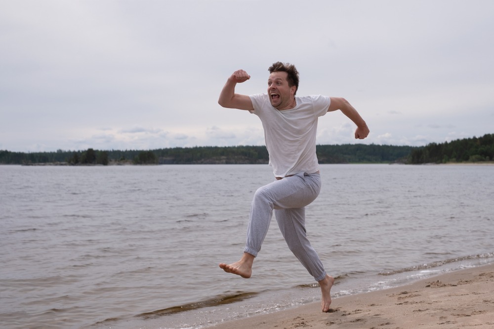 young,caucasian,funny,man,in,fitness,clothing,running,along,sandy
