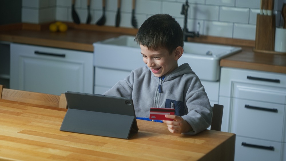 sneaky,little,boy,buys,toys,or,video,game,with,tablet