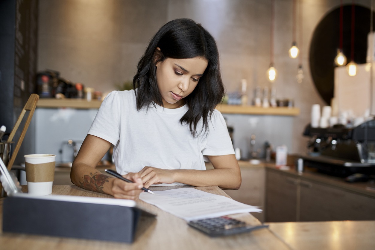 female cafe owner signing papers calculating business expenses