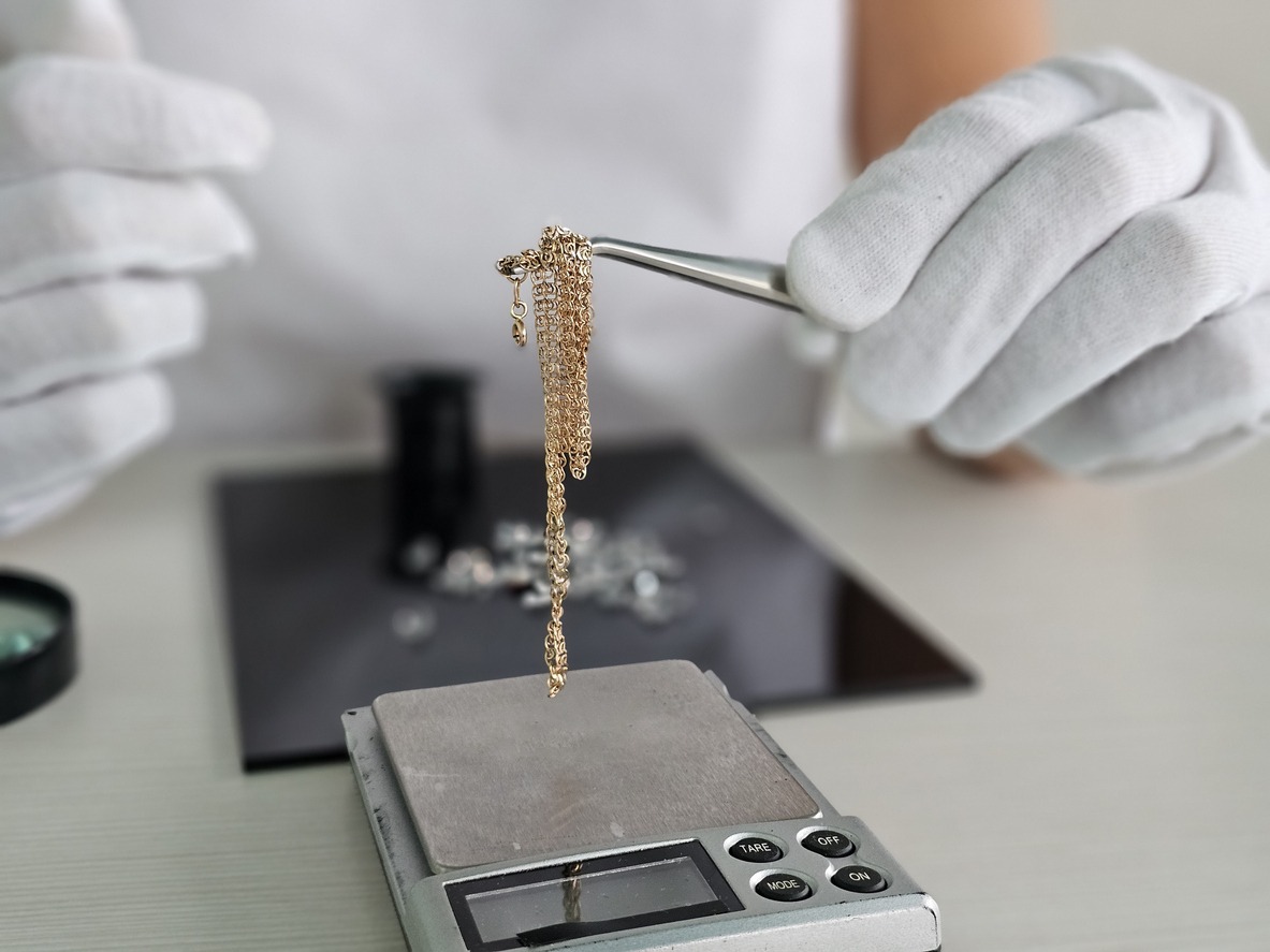 jeweler weighs gold chain in pawn shop on scales