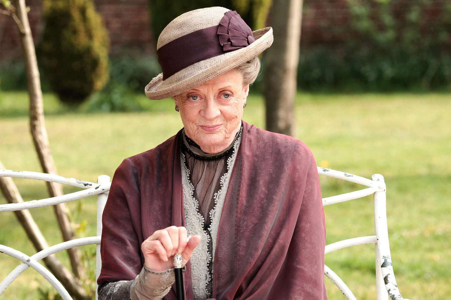 Dame Maggie Smith dressed regally as the Dowager Countess Violet Crawley in Downton Abbey, adorned in Edwardian-era attire.