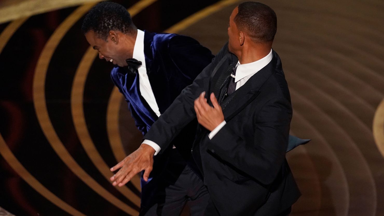 Will Smith slapping Chris Rock on stage during the Oscars ceremony, capturing a tense and shocking moment.