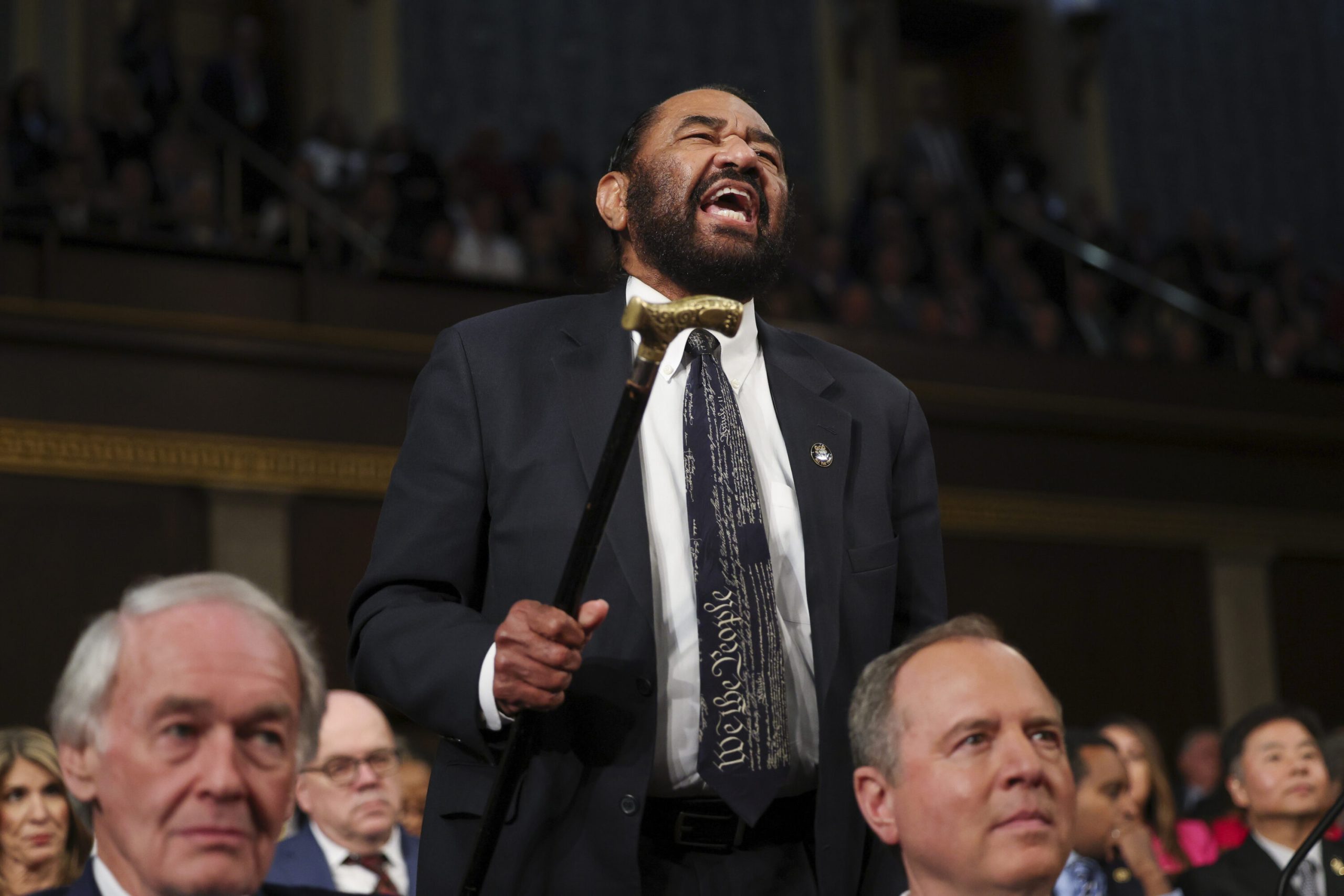 Al Green being escorted out of the House chamber during Donald Trump’s speech, with security personnel guiding him amid a tense atmosphere.