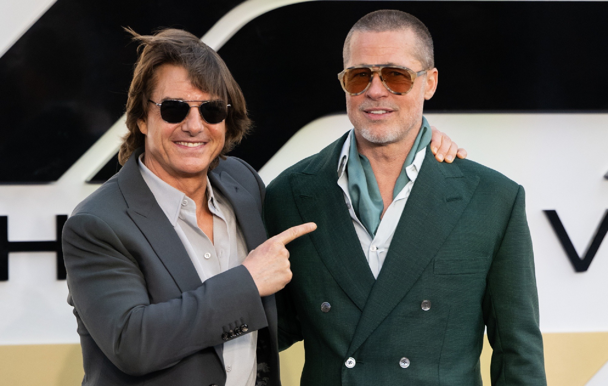 Tom Cruise and Brad Pitt posing together and smiling on the red carpet, dressed in tuxedos.