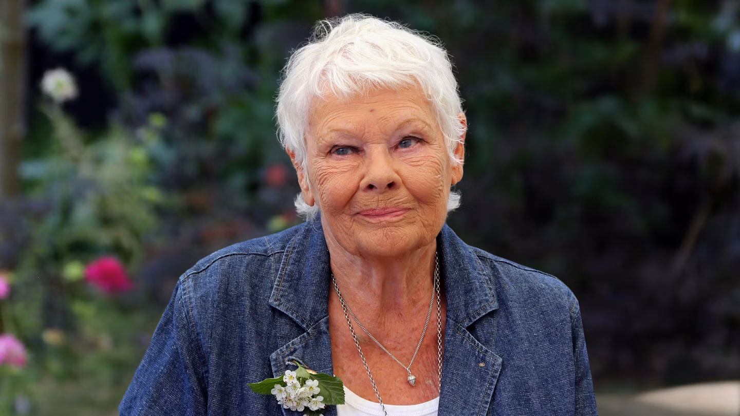 Judi Dench giving a heartfelt interview against a floral backdrop, speaking openly about her declining health.