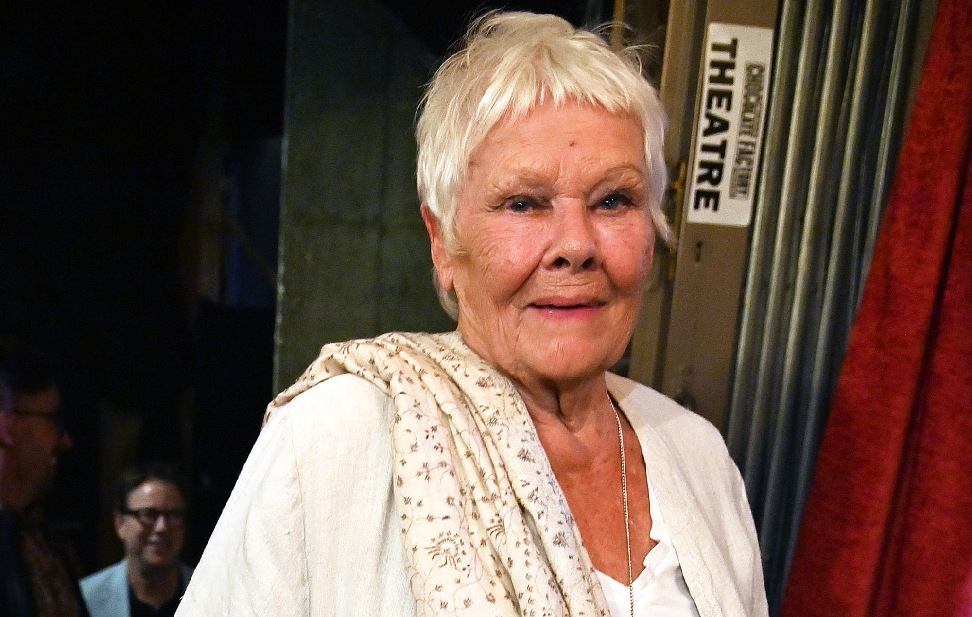 An older Judi Dench smiling warmly for the camera, exuding grace and charm.