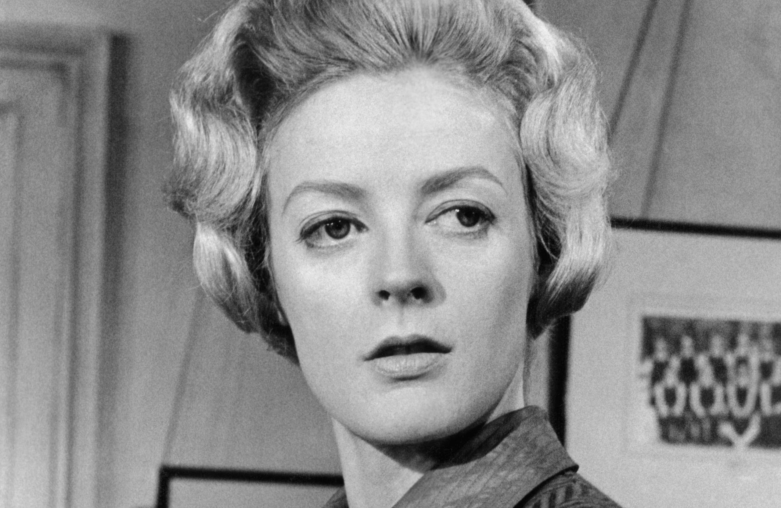 Young Dame Maggie Smith captured in a striking black-and-white portrait, exuding timeless elegance and theatrical intensity.