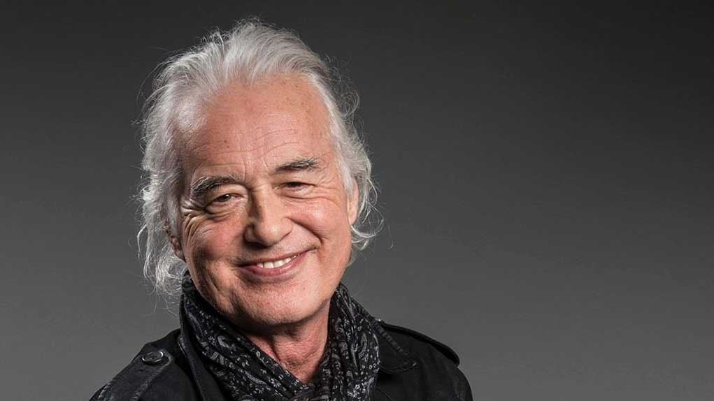 An older Jimmy Page smiling warmly during a professional photoshoot, exuding charm and rock legend confidence.