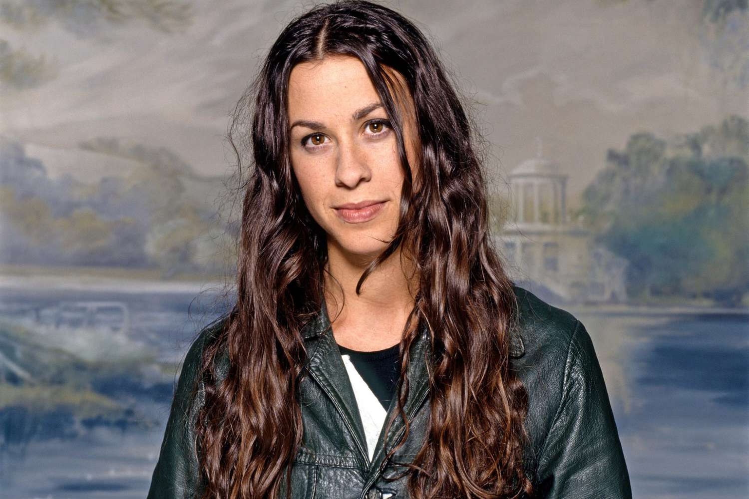 Alanis Morissette posing confidently during a photoshoot, wearing a stylish leather jacket.