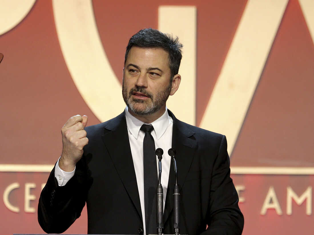 Jimmy Kimmel speaks on stage at the 31st Annual Producers Guild Awards, wearing a sharp suit and addressing a packed audience.
