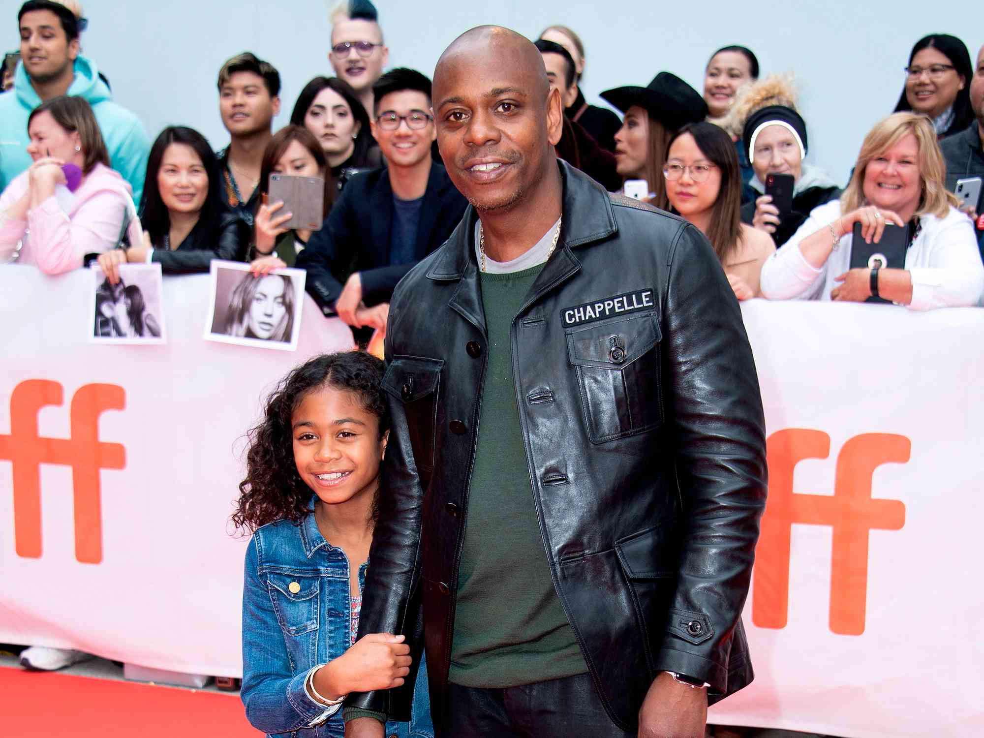 Dave Chappelle and his daughter share a proud moment on the red carpet, smiling for cameras at a major entertainment event.