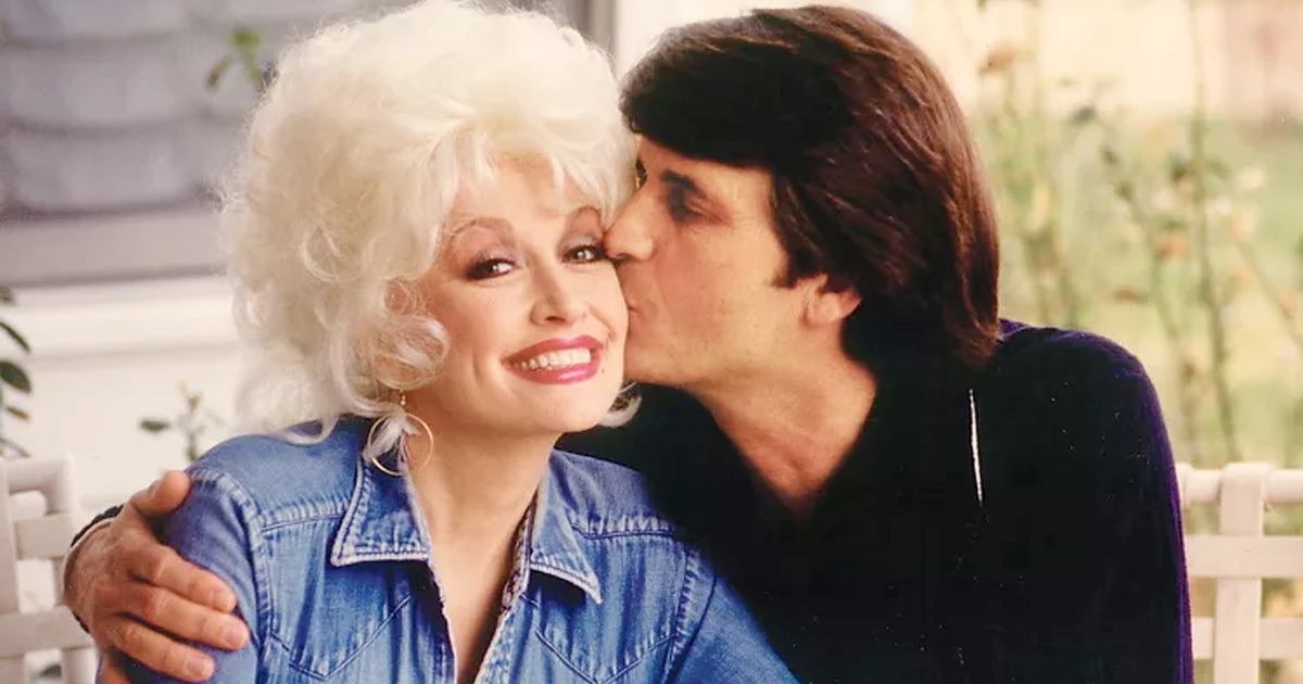 Dolly Parton smiles warmly while her husband Carl Dean kisses her cheek in a rare, affectionate photo of the couple.
