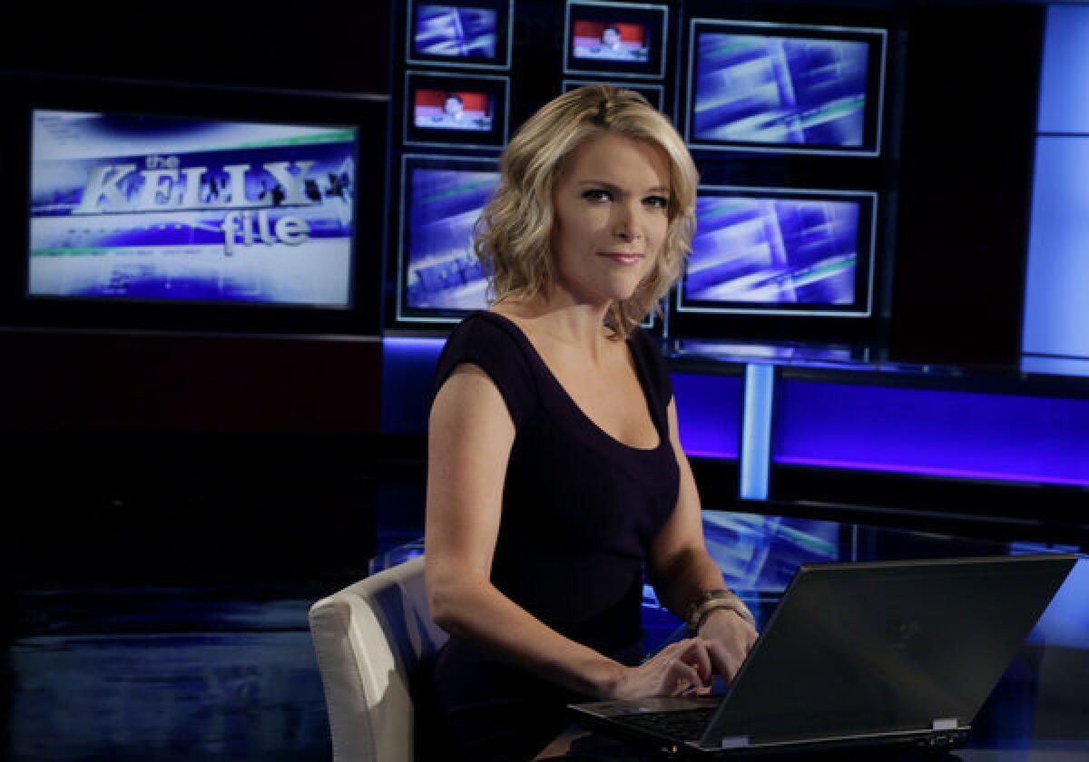 Megyn Kelly seated at her news desk, dressed smartly with multiple screens glowing behind her in the studio.