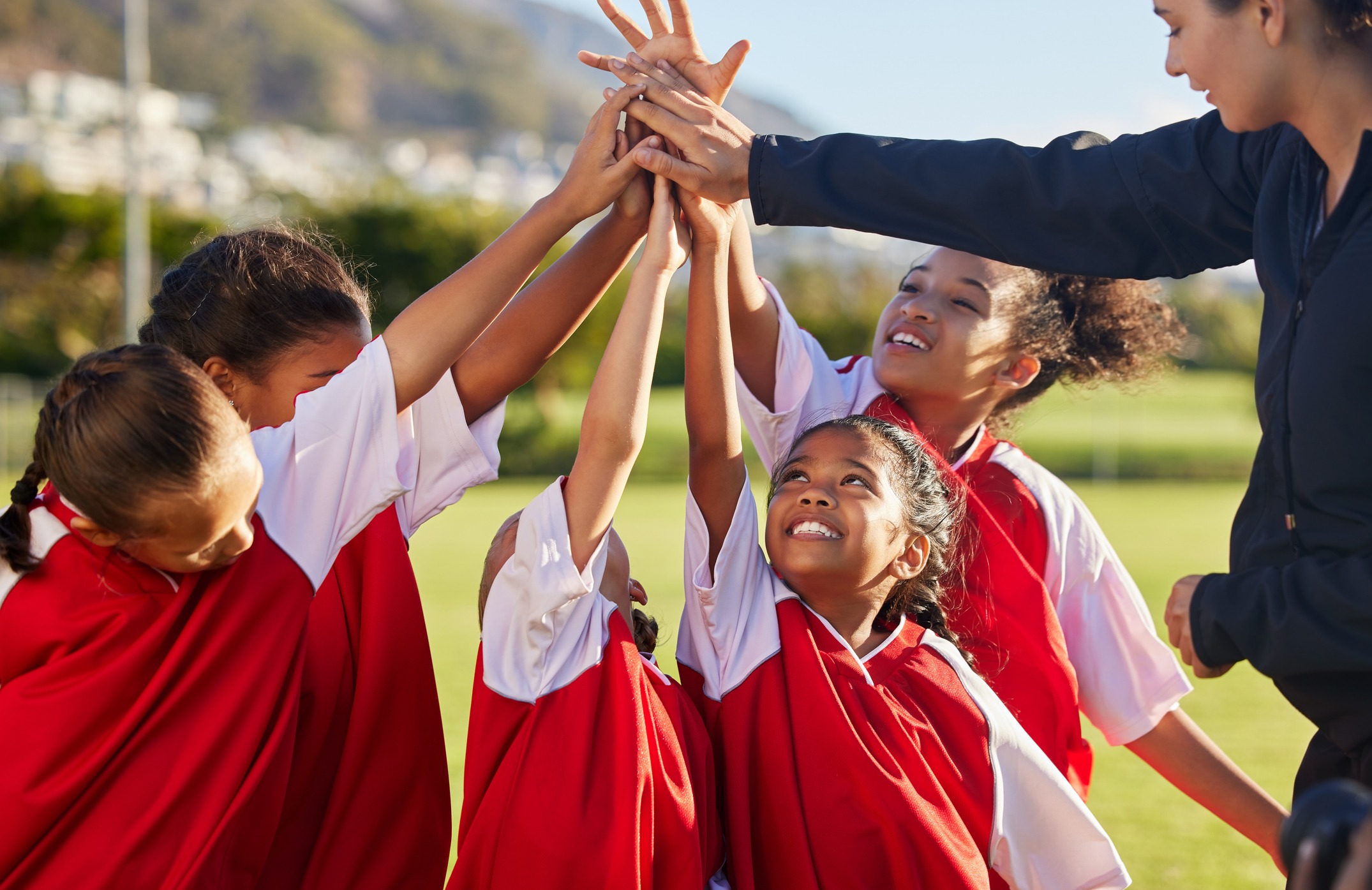 high five, team and girls soccer celebrate a victory and win on field with coach. sports. young and female children smile, relax and happy they won soccer match with training, teamwork and together.