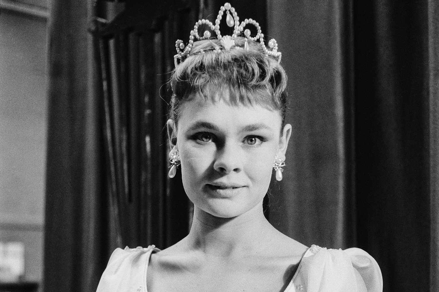 A young Judi Dench wearing a sparkling tiara, radiating elegance and grace.