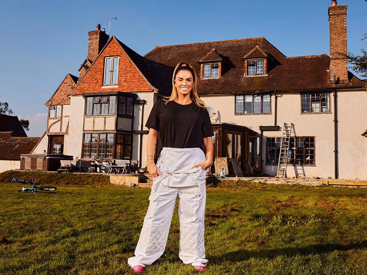 Katie Price standing outside her £4,500-per-month rental home in Sussex, dressed casually with her children’s belongings nearby.