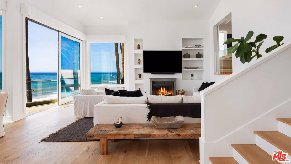 Elegant living room with modern furnishings, a sleek fireplace, and expansive glass doors revealing panoramic ocean views.