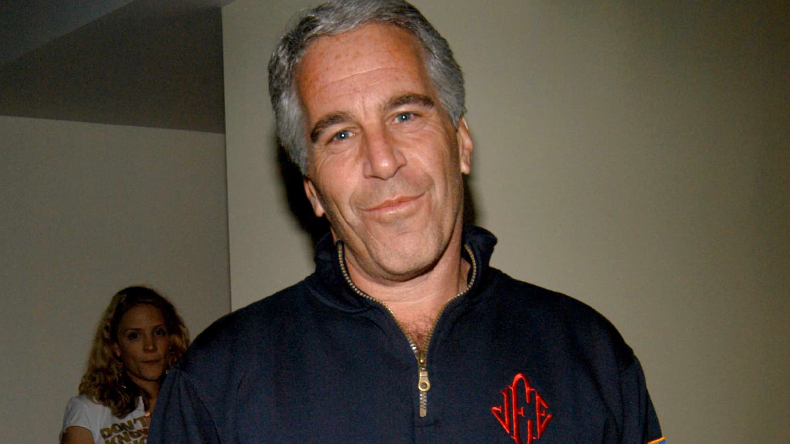 Close-up image of Jeffrey Epstein smirking, wearing a fleece and looking directly at the camera.