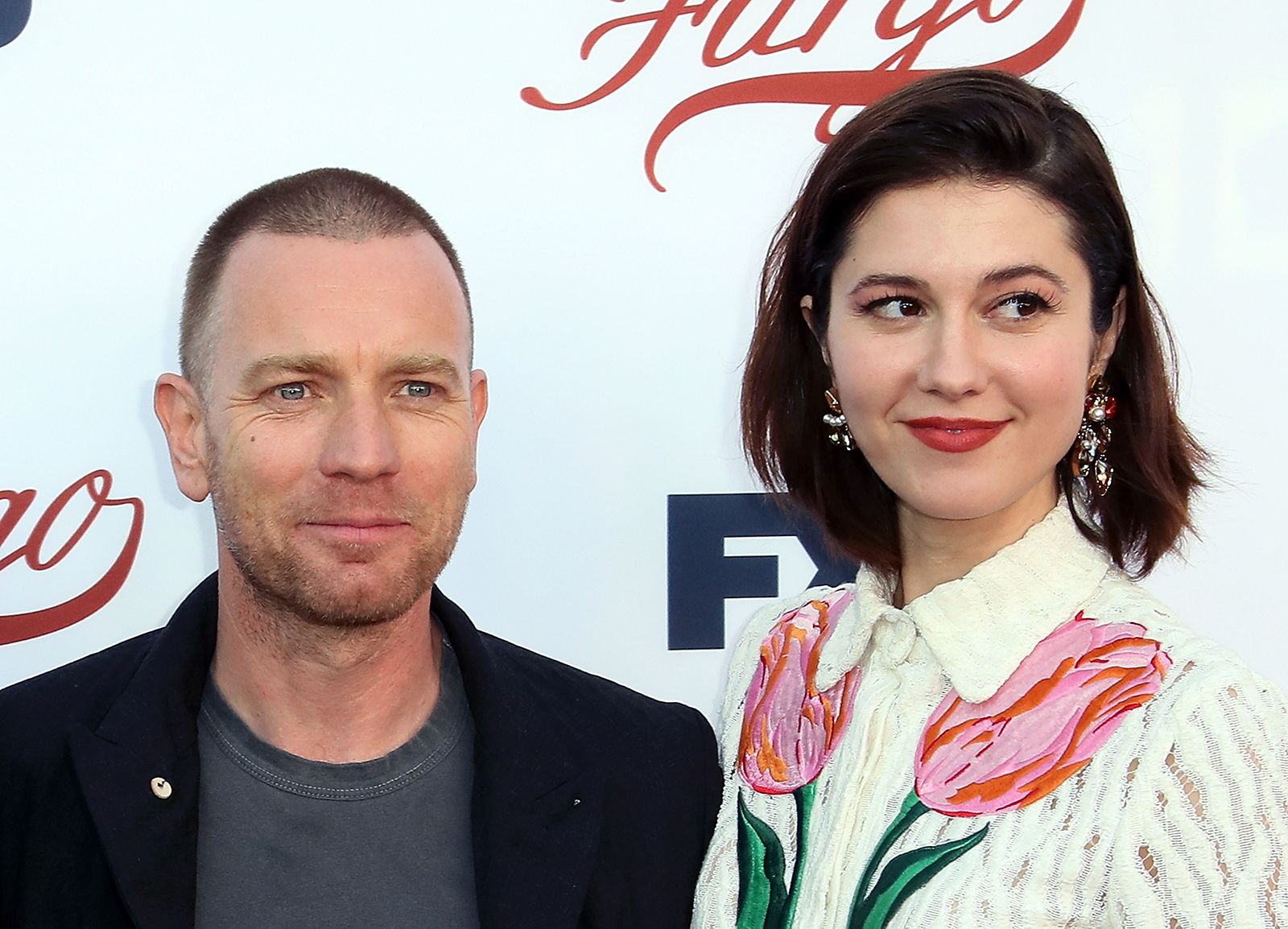 Ewan McGregor and his partner Mary Elizabeth Winstead posing together on the red carpet, dressed in elegant evening attire.