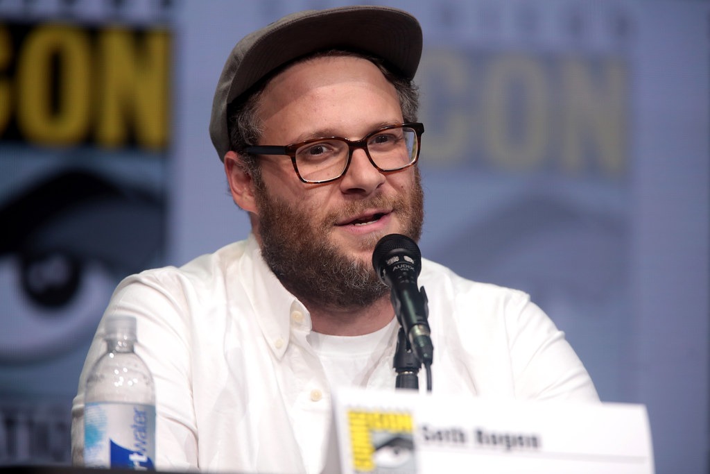 Seth Rogen engaging with fans during a lively panel at Comic-Con, surrounded by enthusiastic attendees.