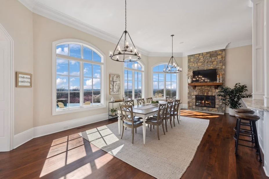 An elegant dining room with a large table, stylish chairs, and a sophisticated chandelier in Dave Ramsey’s Tennessee estate.
