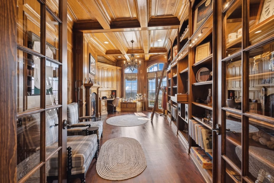 A sophisticated wood-paneled home office with a large desk, bookshelves, and comfortable seating in Dave Ramsey’s Tennessee estate.